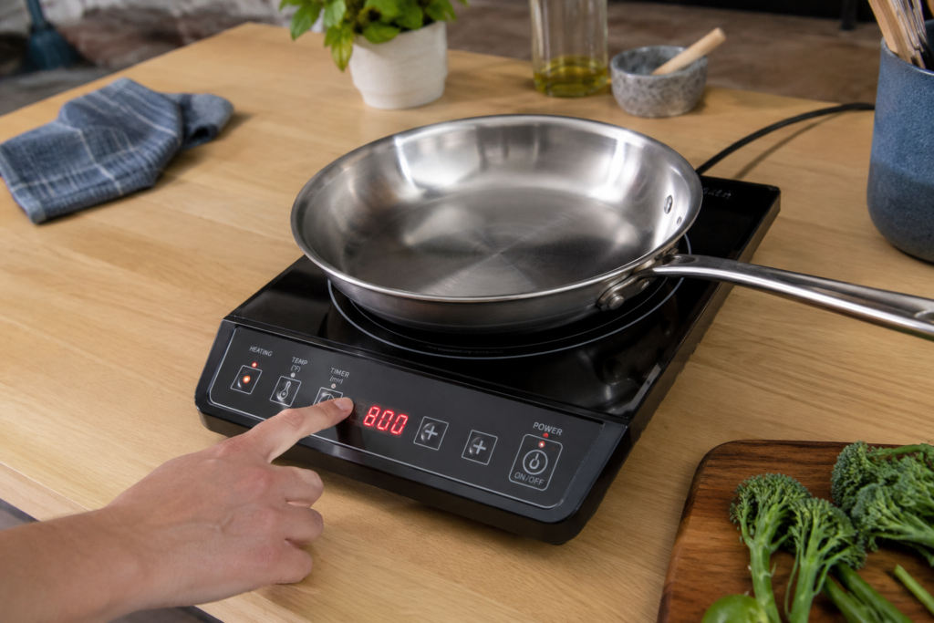 Portable induction cooktop with stainless steel pan on kitchen counter — single burner buying guide